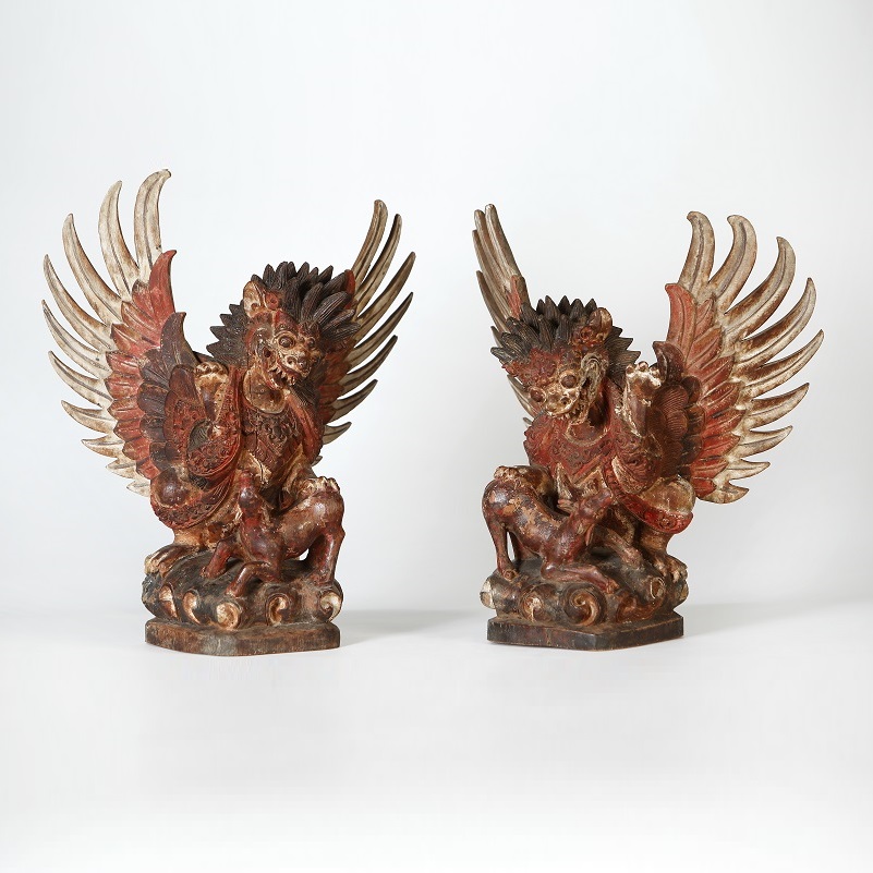 Pair of winged singa lions, each with a paw on a deer